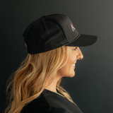 Woman wearing a black cap with a logo on a dark background