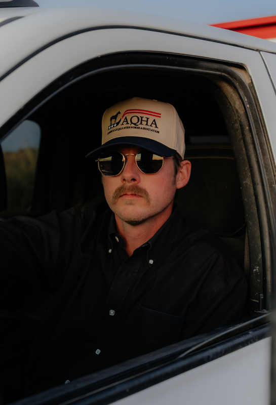Man wearing a cap and sunglasses sitting inside a vehicle